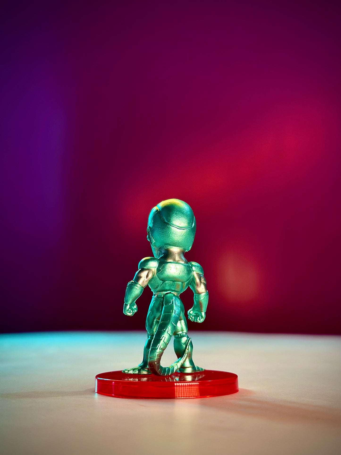 Metallic alien figure on a red base against a gradient purple to red background