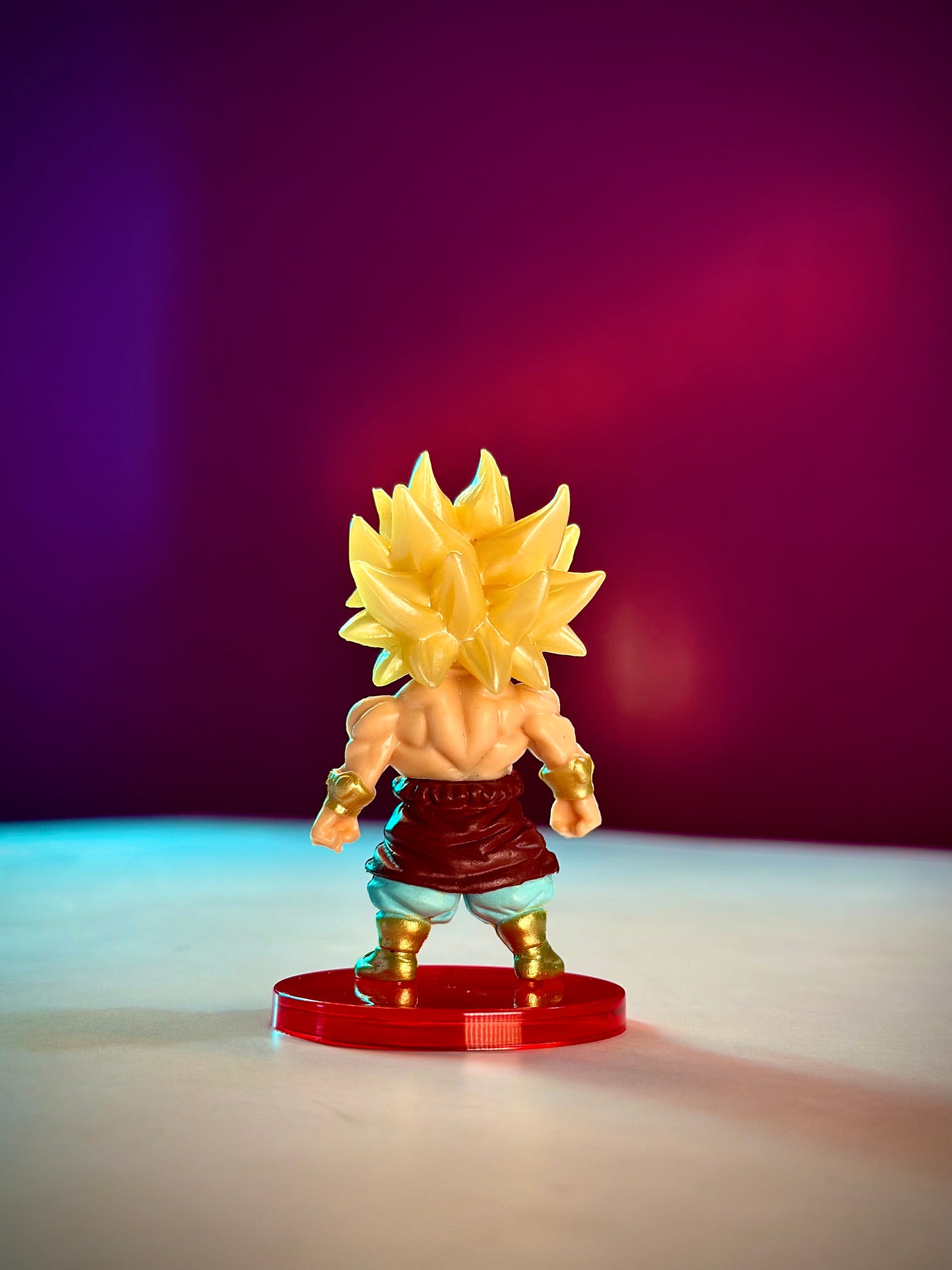 Super Saiyan character figurine on a red base against a gradient purple and blue background