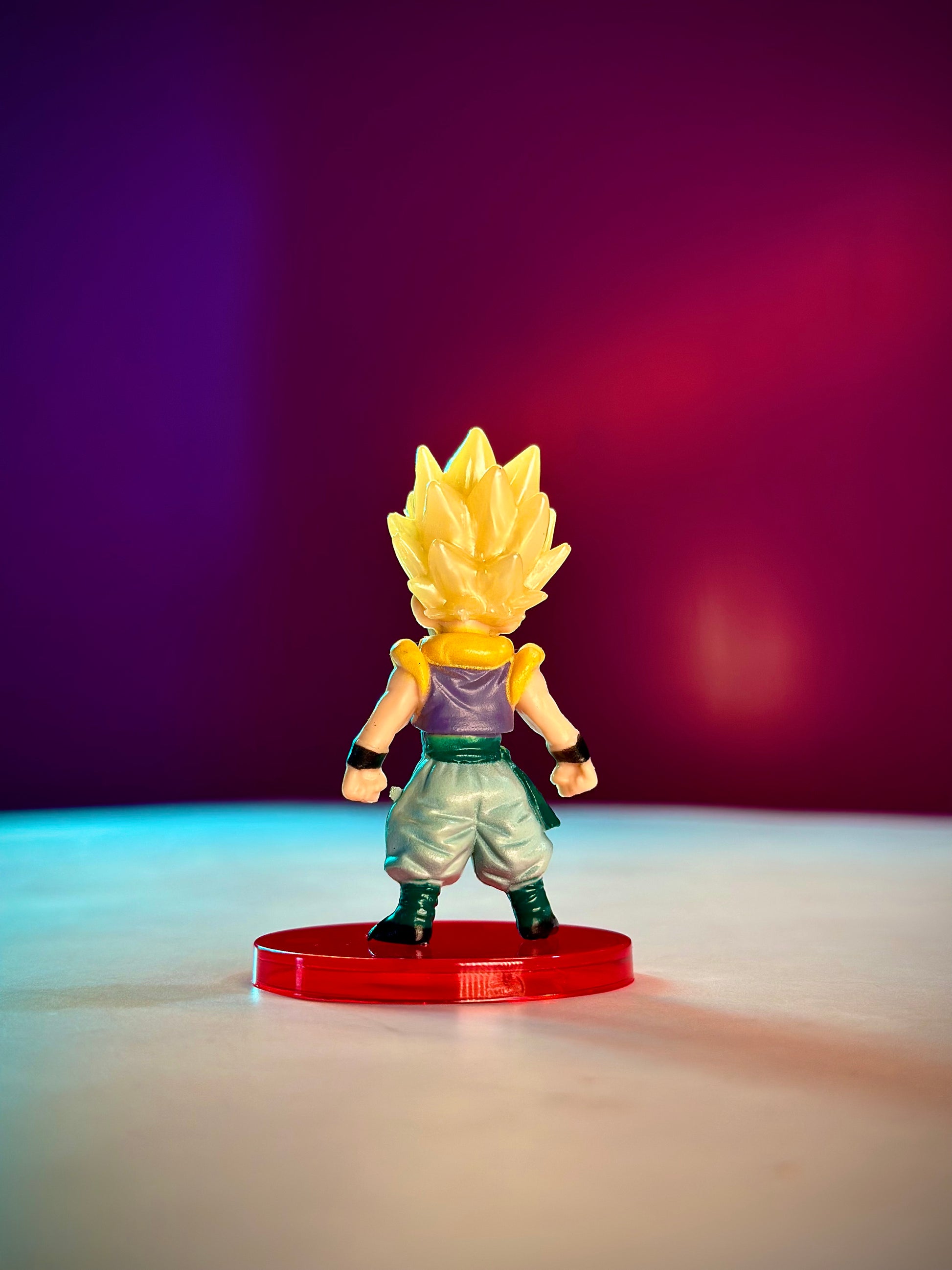 Super Saiyan figure on a red base against a gradient purple to pink background
