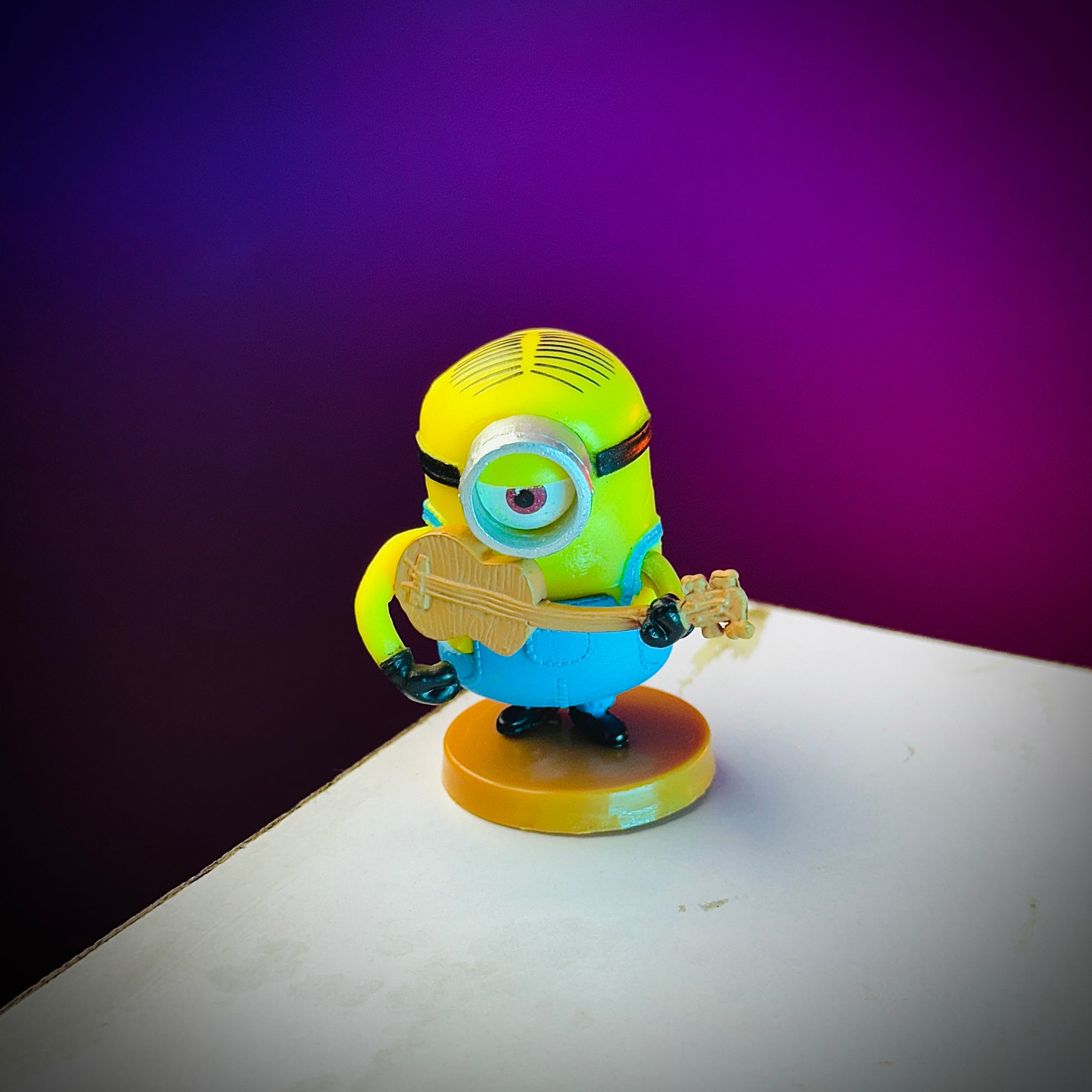 Minion toy figure holding a guitar on a purple and white background