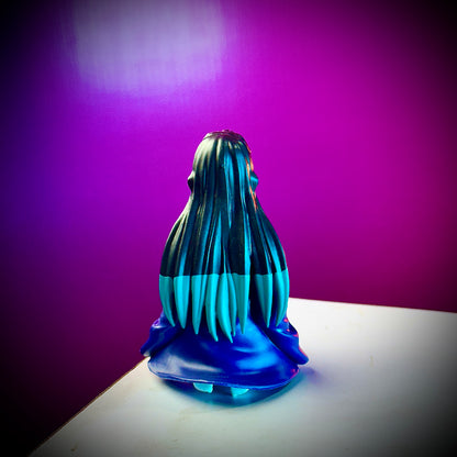 Blue and black figurine with long hair on a white surface against a purple background