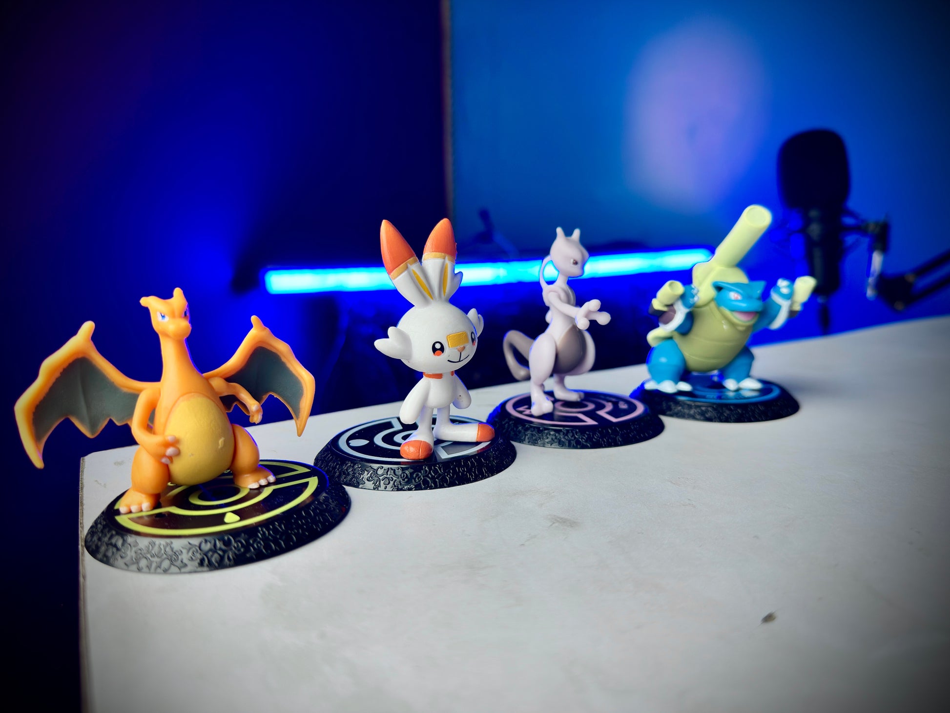 Four Pokemon mini figures including Charizard Mewtwo Blastoise and Scorbunny on display bases
