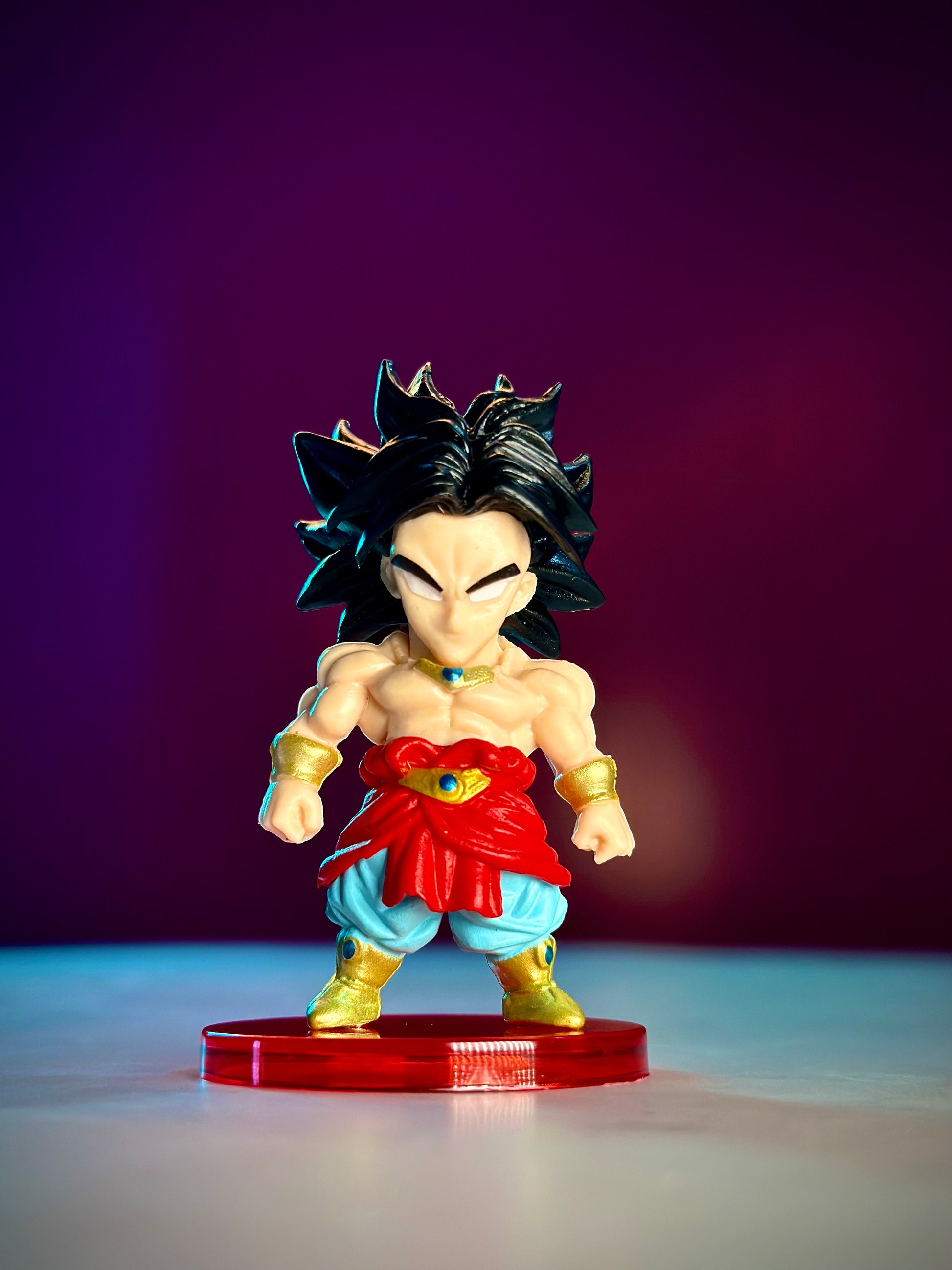 Action figure with spiky black hair and red outfit on a purple gradient background