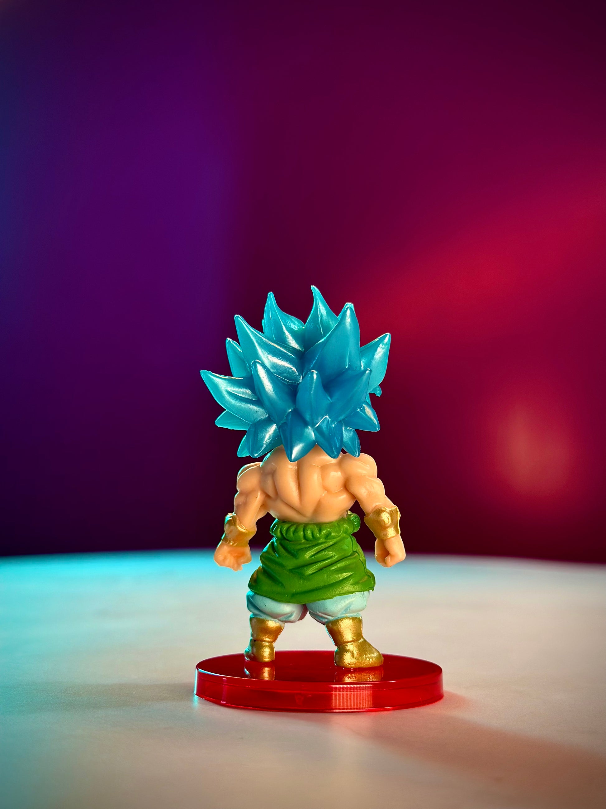 Super Saiyan Blue character figurine on a red base with a gradient purple to red background