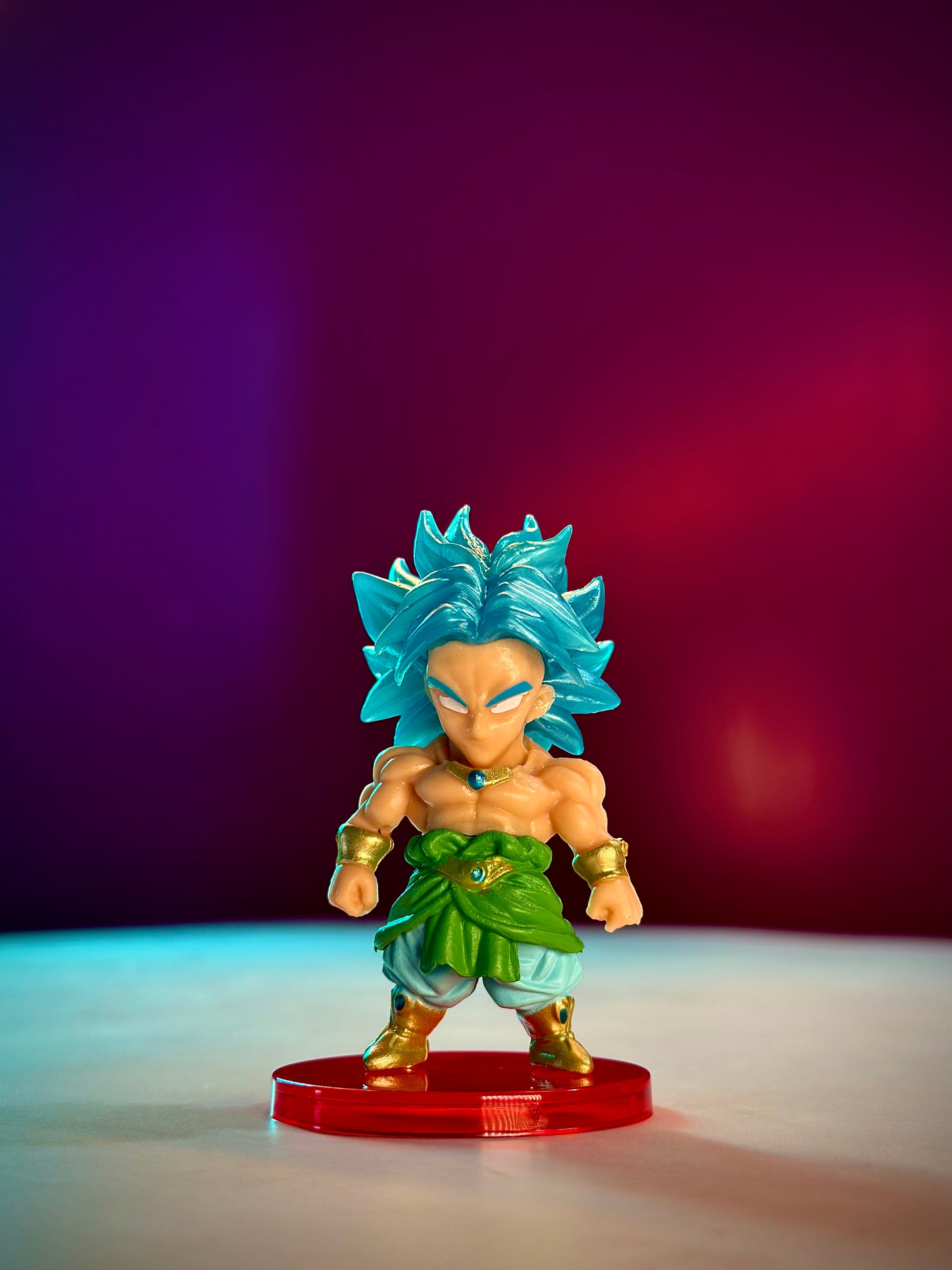 Super Saiyan Blue character figurine on a red base with a gradient purple to red background