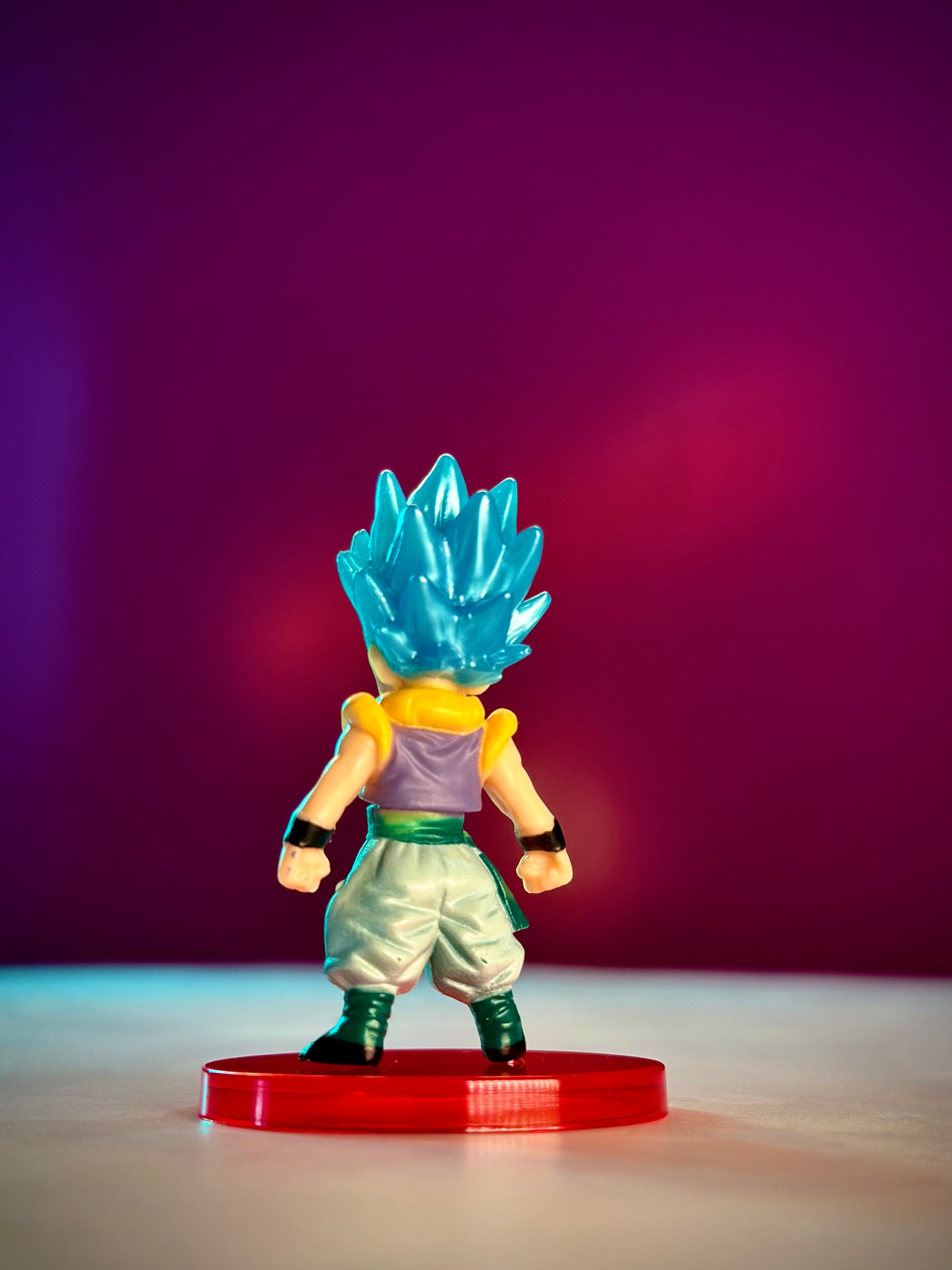Toy figure with blue hair on a red base against a purple background